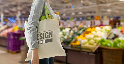 A person holding a bag of food in front of produce.